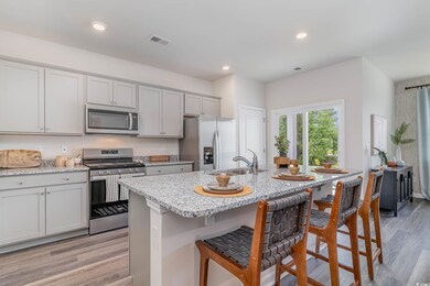 Kitchen with stainless steel appliances, light stone counters, light wood finished floors, a breakfast bar, and recessed lighting
