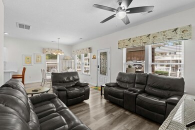 Living area featuring wood finished floors, a textured ceiling, a chandelier, and ceiling fan