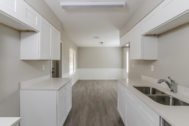 Kitchen with light countertops, dark wood finished floors, and white cabinets