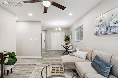 Living area with light wood-style flooring, ceiling fan, baseboards, a chandelier, and recessed lighting