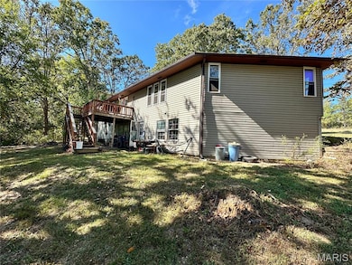 View of side of property featuring a wooden deck, stairs, and a yard