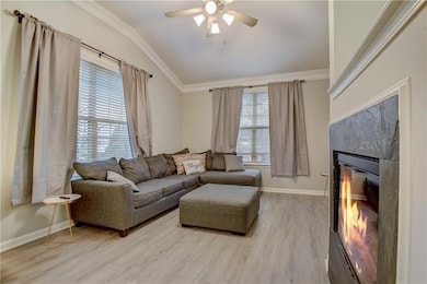Living room with ornamental molding, vaulted ceiling, light wood-style floors, and a premium fireplace
