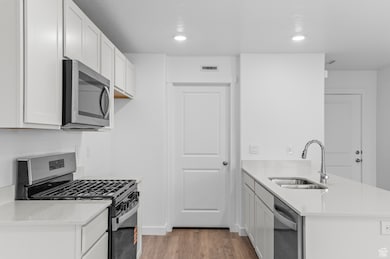 Kitchen featuring stainless steel appliances, a peninsula, light wood-style flooring, recessed lighting, and white cabinets