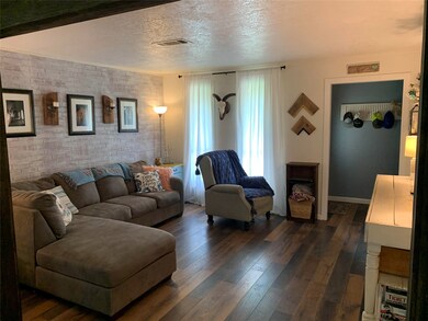 View of living room from dining room showing brick accent wall