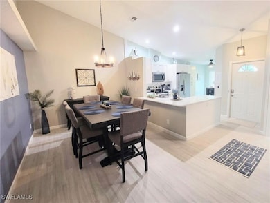 Dining space with vaulted ceiling, light wood-style flooring, recessed lighting, and a chandelier