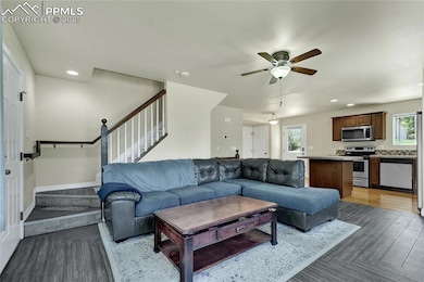 Living room with stairs, ceiling fan, recessed lighting, and wood finished floors