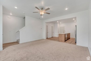 Unfurnished living room with light colored carpet, recessed lighting, a ceiling fan, and stairway