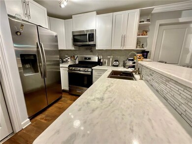 Kitchen featuring white cabinetry, tasteful backsplash, open shelves, stainless steel appliances, and a sink