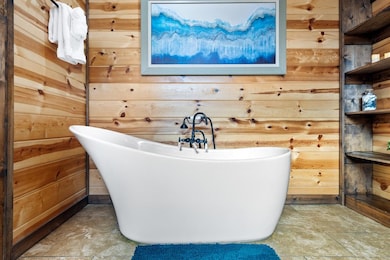Bathroom featuring a freestanding bath and wood walls