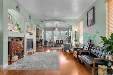 Living area with a tiled fireplace, wood finished floors, and arched walkways