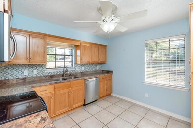 Kitchen with ceiling fan, backsplash, a textured ceiling, sink, and stainless steel appliances