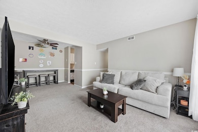 Living area with carpet flooring, a ceiling fan, and a textured ceiling
