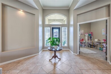 Foyer with light tile patterned floors, crown mold