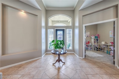 Foyer with light tile patterned floors, crown molding, and baseboards