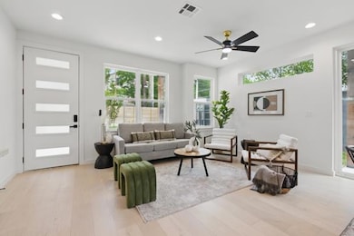 Living area with a ceiling fan, visible vents, re