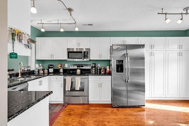 Kitchen with white cabinets, track lighting, visib