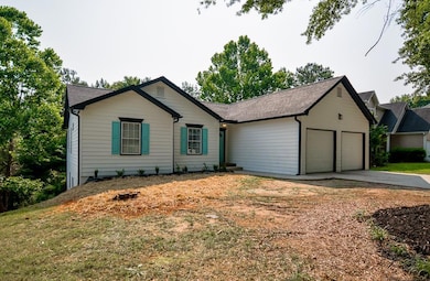 Ranch-style house with an attached garage, driveway, and a shingled roof