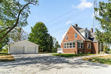 View of side of home with a detached garage, brick siding, an outbuilding, and a chimney