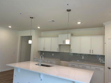 Kitchen with ornamental molding, white cabinetry, a center island with sink, decorative backsplash, and recessed lighting