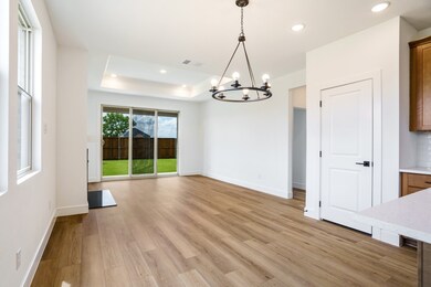 Unfurnished dining area featuring a chandelier, light wood finished floors, baseboards, a tray ceiling, and recessed lighting