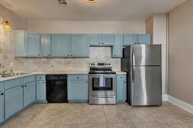 Kitchen featuring appliances with stainless steel finishes, blue cabinets, and backsplash