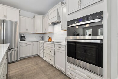 Kitchen with light countertops, appliances with stainless steel finishes, light wood finished floors, and tasteful backsplash