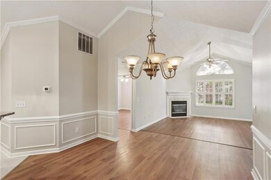 Unfurnished living room with lofted ceiling, wood finished floors, ceiling fan, a chandelier, and a tiled fireplace