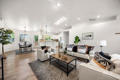 Living area featuring vaulted ceiling, light wood-style floors, a skylight, recessed lighting, and a chandelier