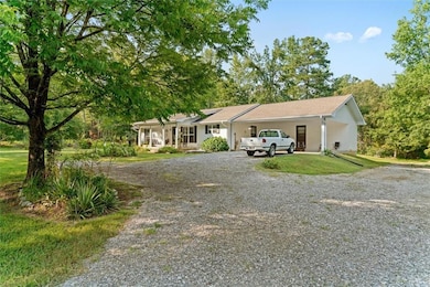 Ranch-style home with driveway, covered porch, a front yard, and a carport