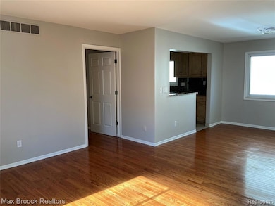 Unfurnished living room with wood finished floors and baseboards