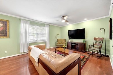 Living area with wood finished floors, ceiling fan, ornamental molding, and recessed lighting