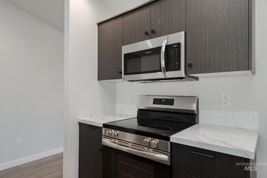 Kitchen with stainless steel appliances, light countertops, light wood finished floors, and dark brown cabinetry