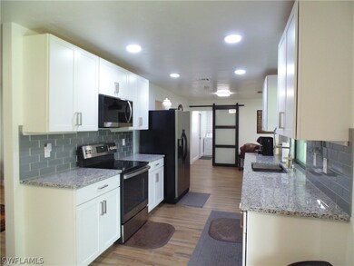 Kitchen with stainless steel appliances, hardwood / wood-style flooring, a barn door, sink, and tasteful backsplash