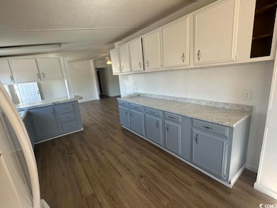 Kitchen with a textured ceiling, dark wood-type fl