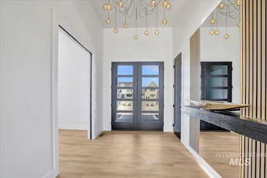 Entrance foyer with a chandelier, french doors, and wood finished floors