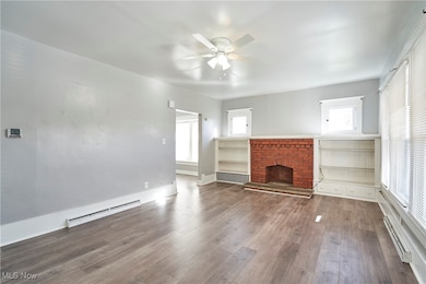 Unfurnished living room with baseboard heating, a fireplace, and plenty of natural light