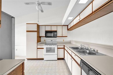 Kitchen featuring white appliances, a sink, light 