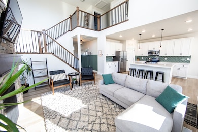 Living room featuring light wood finished floors, a high ceiling, stairs, and recessed lighting