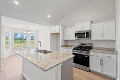 Kitchen featuring appliances with stainless steel finishes, light stone counters, recessed lighting, light wood-style floors, and a kitchen island with sink