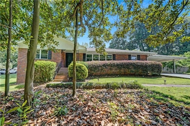 View of front facade with brick siding, a carport, and a front lawn