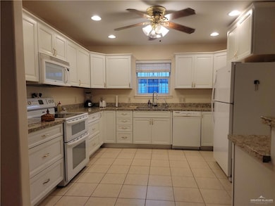 Kitchen with white appliances, white cabinetry, ceiling fan, recessed lighting, and dark stone countertops