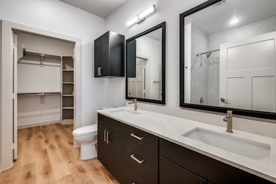 Bathroom with wood finished floors, a shower, double vanity, and a spacious closet
