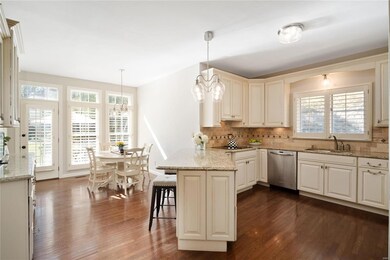 Beautiful updated kitchen features white glazed cabinetry, custom tile backsplash, nickel hardware and lighting, stainless appliances, wood flooring, floor-to-ceiling windows and walks out to patio and private backyard.