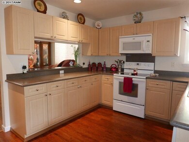 Kitchen has light cabinetry with dark grey counter