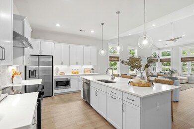 Kitchen featuring stainless steel appliances, white cabinetry, decorative light fixtures, tasteful backsplash, and recessed lighting