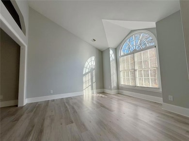 Unfurnished room with light wood finished floors and high vaulted ceiling