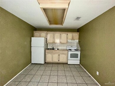 Kitchen with light brown cabinets, backsplash, white appliances, and light tile patterned flooring