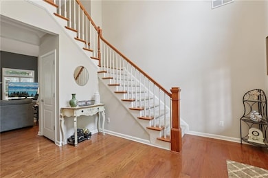 Staircase featuring wood finished floors, baseboards, and a towering ceiling