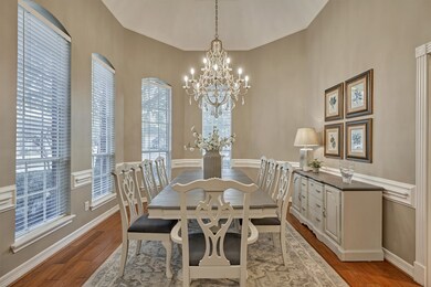 Formal dining room is warm and inviting, featuring chair rail, an array of windows and an elegant chandelier.