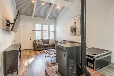 Living room featuring light wood-style floors, wooden ceiling, and a wood stove